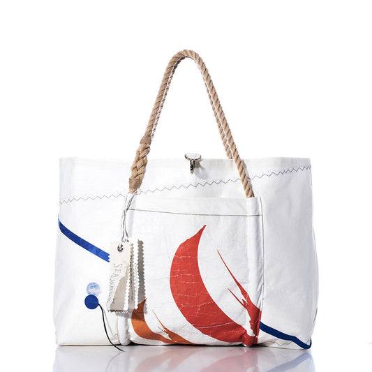 Sea Bags’ Vintage Orange Graphic Wharf Tote features rope handles, a front pocket, a hanging tag, and showcases an abstract orange vintage graphic on the front. Handcrafted in Portland, Maine from recycled sails, this tote brings nautical charm to everyday style. The background is plain white. by Sea Bags