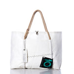 Introducing the Sea Bags Vintage Quantum Wharf Tote—a white, handmade tote bag crafted in Portland, Maine from recycled sail material. This eco-friendly design features rope handles, a convenient front pocket, the signature SEA BAGS tag, and a distinctive black and green patch near the bottom right corner. The Vintage Quantum Wharf Tote combines practical style with sustainable craftsmanship. by Sea Bags