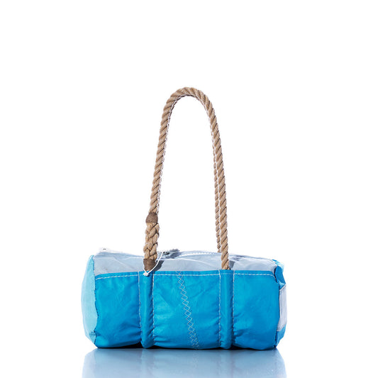 The Sea Bags Vintage Blue Baguette Bag, crafted from recycled sails with white stitching and two tan hand-spliced hemp rope handles, is displayed on a white reflective surface. by Sea Bags
