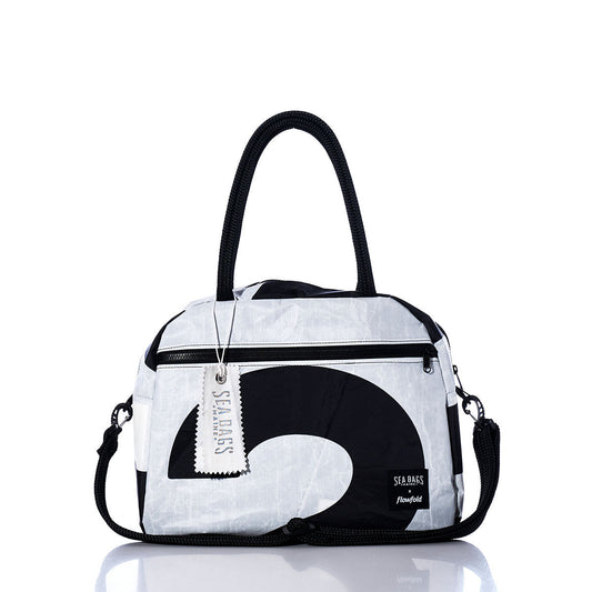 The Sea Bags Vintage Black 2 Essential Weekender Travel Bag is a white and black duffel featuring black handles, a front zipper pocket, and a removable shoulder strap. Perfect as a Weekender Travel Bag, it includes a white SEABAGS tag hanging from the handle and is reflected on the surface. by Sea Bags