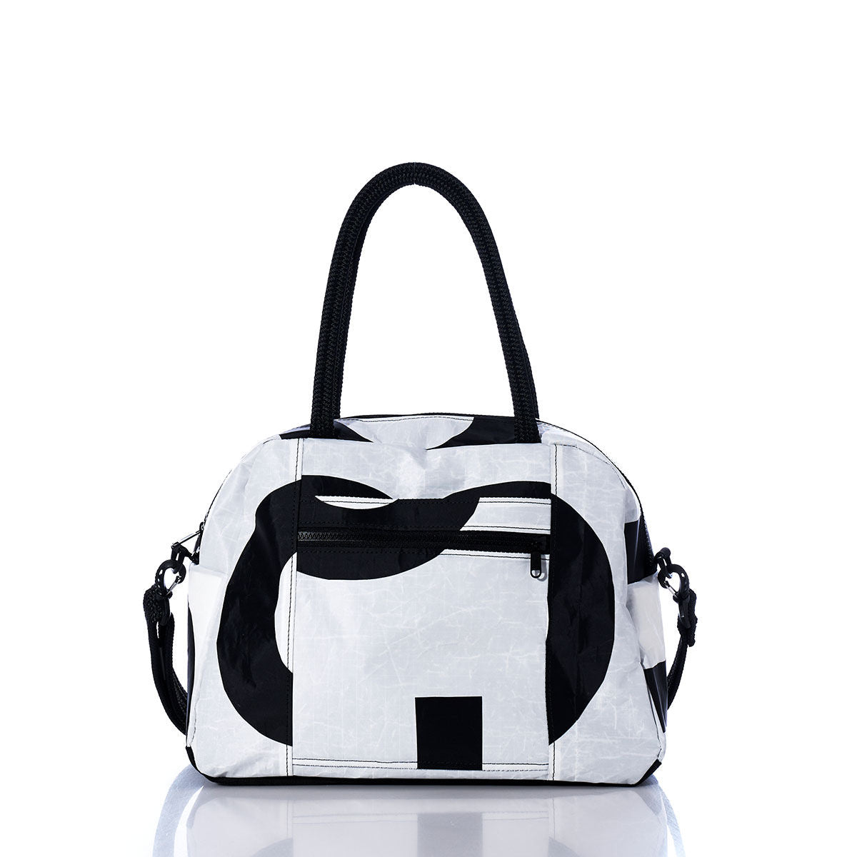The Sea Bags Vintage Black and White Essential Weekender Travel Bag, featuring striking black abstract patterns on a white background, black handles, a front zip pocket, and side clips—ideal as an Essential Weekender Travel Bag or convenient carryon—is displayed on a reflective surface against a white backdrop. by Sea Bags