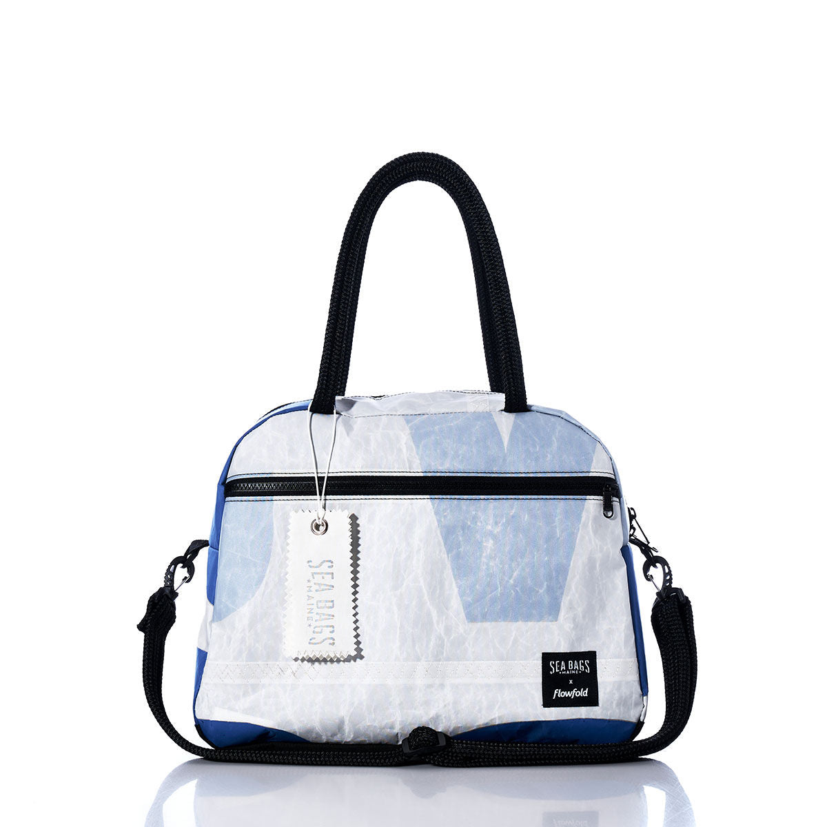 The Vintage Blue and White Essential Weekender Travel Bag by Sea Bags features black handles, a detachable shoulder strap, and a prominent Sea Bags brand tag. Photographed on a reflective white background, it’s the ideal overnight or weekender travel bag for your next getaway. by Sea Bags