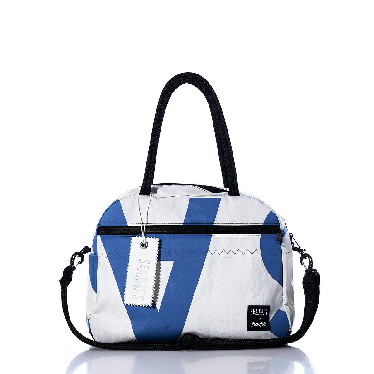 The Sea Bags Vintage Blue A Essential Weekender Travel Bag features a white and blue design with black handles, a detachable shoulder strap, and the distinctive Sea Bags tag and logo on the front. Designed as a compact carry-on, this versatile travel bag is ideal for short getaways and includes a handy trolley sleeve for easy attachment to your luggage. by Sea Bags