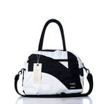 The Sea Bags Vintage Black 7 Essential Weekender Travel Bag features a classic black-and-white design with dual black handles, a shoulder strap, front zipper pocket, and an attached Sea Bags tag. Perfectly sized for use as an overnight bag or weekender travel companion, it is displayed against a white background. by Sea Bags