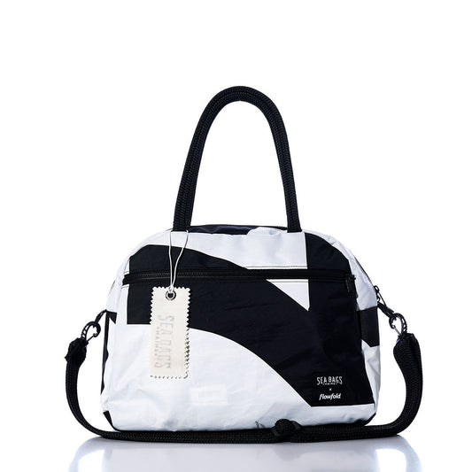 The Sea Bags Vintage Black 7 Essential Weekender Travel Bag features a classic black-and-white design with dual black handles, a shoulder strap, front zipper pocket, and an attached Sea Bags tag. Perfectly sized for use as an overnight bag or weekender travel companion, it is displayed against a white background. by Sea Bags