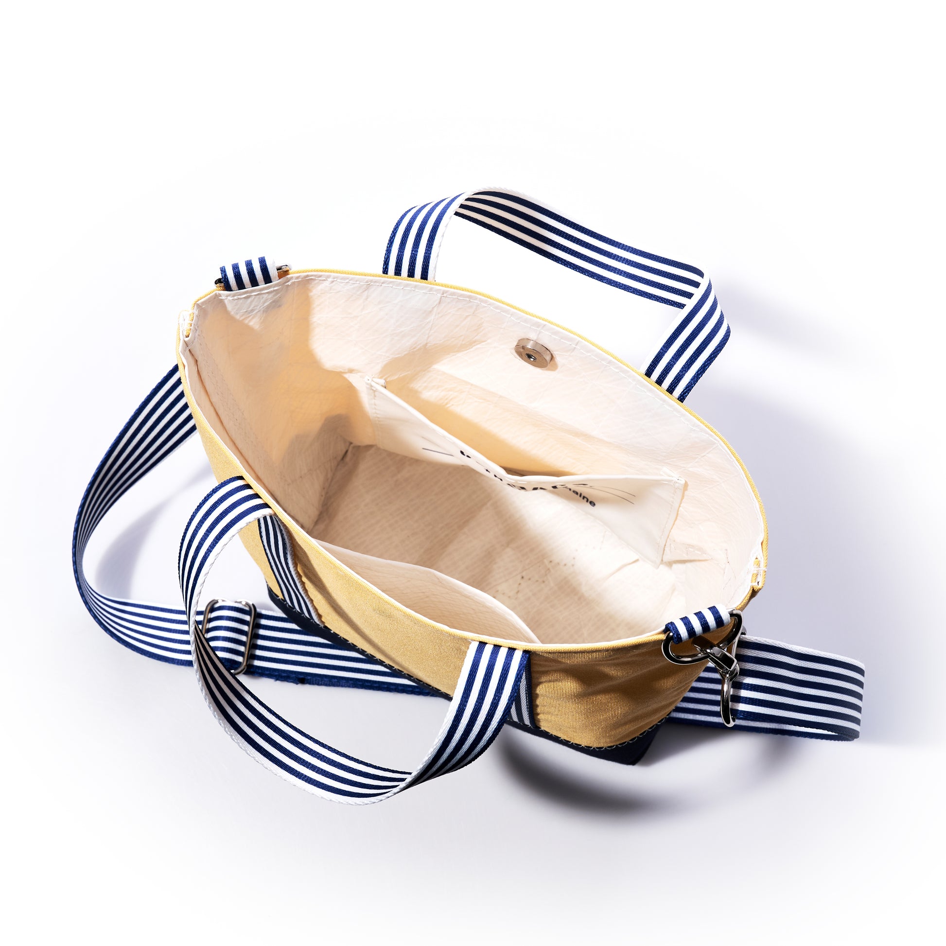 Open butter yellow Vintage Yellow Canvas Crossbody Tote by Sea Bags, featuring striped blue and white straps and an empty interior with small side pockets, displayed on a white background—a fresh addition to the heritage collection bag line. by Sea Bags