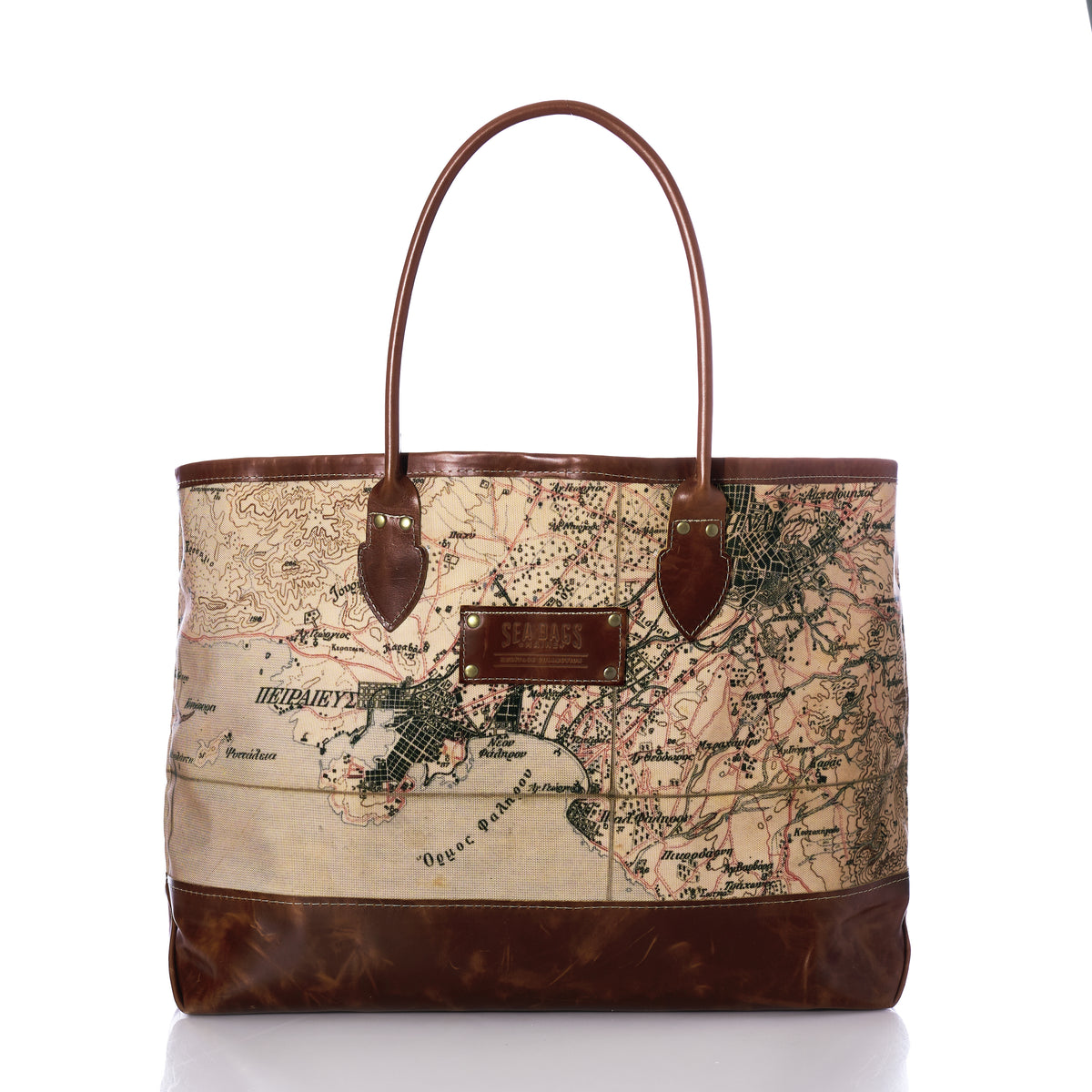 The Heritage Aello Large Tote by Sea Bags features leather handles and trim, with a printed vintage map design on the front inspired by the legendary voyages of the iconic Greek sailing yacht S/Y AELLO, all set against a white background.