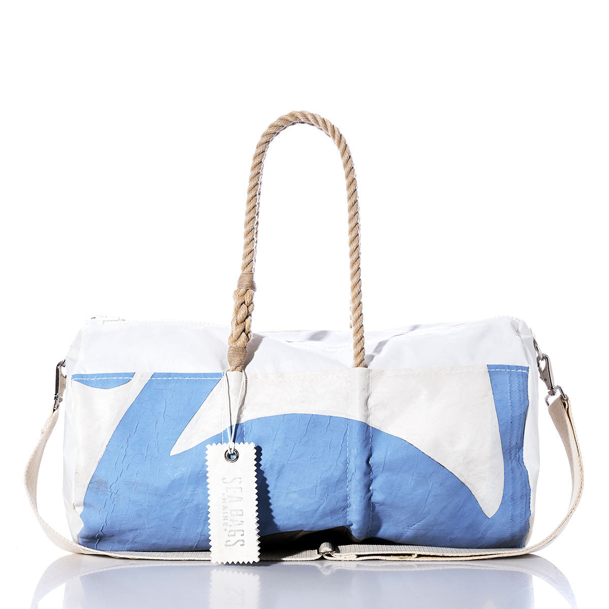 The Vintage Blue and White Duffel by Sea Bags is crafted from recycled sail cloth, featuring hemp rope handles, a detachable shoulder strap, and a Sail Bags tag attached to one handle, shown against a white background. by Sea Bags