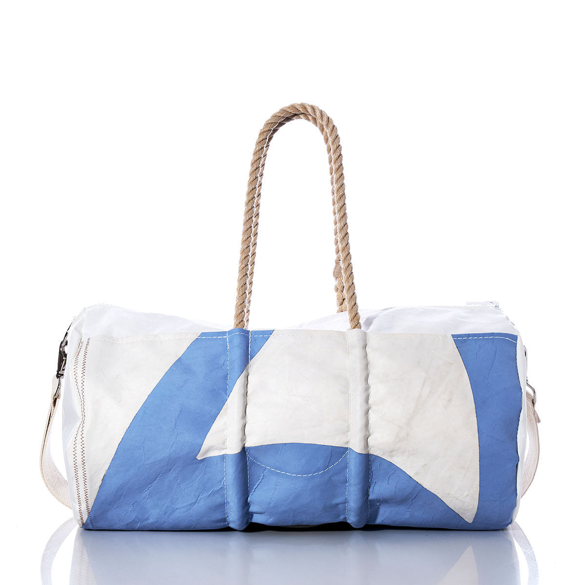 The Sea Bags Vintage Blue and White Duffel, crafted from recycled white and blue sail cloth with durable hemp rope handles and a minimalist geometric pattern, is shown on a reflective surface. by Sea Bags