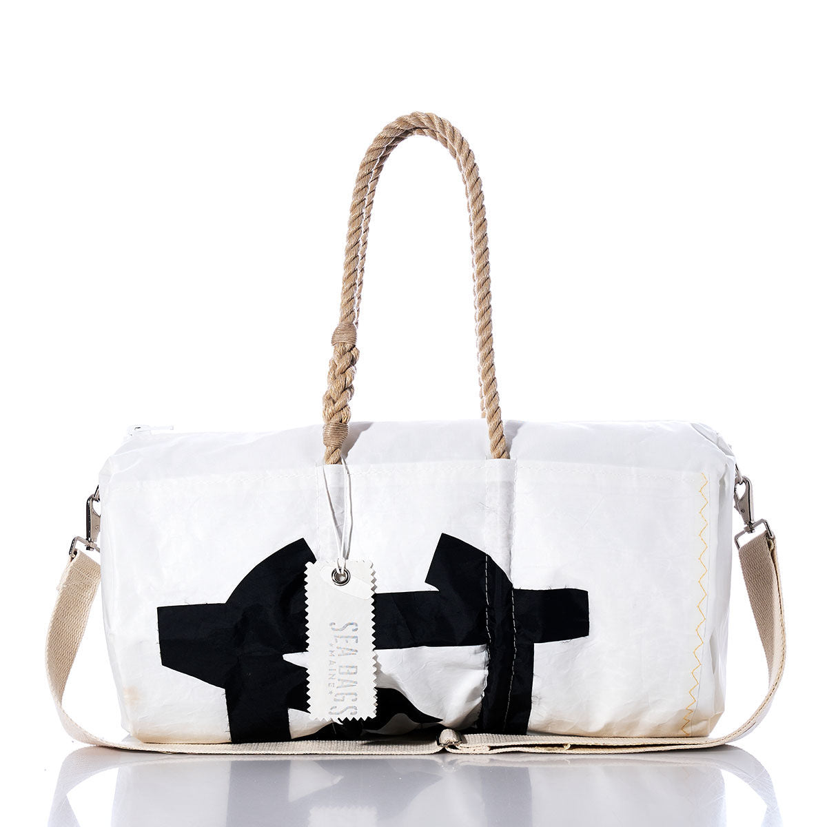 Vintage Melges Duffel by Sea Bags—crafted from recycled sail cloth, this white duffel bag showcases a bold black abstract design and is equipped with durable hemp rope handles, a beige shoulder strap, and a white “Sea Bags” tag attached to the handle. by Sea Bags