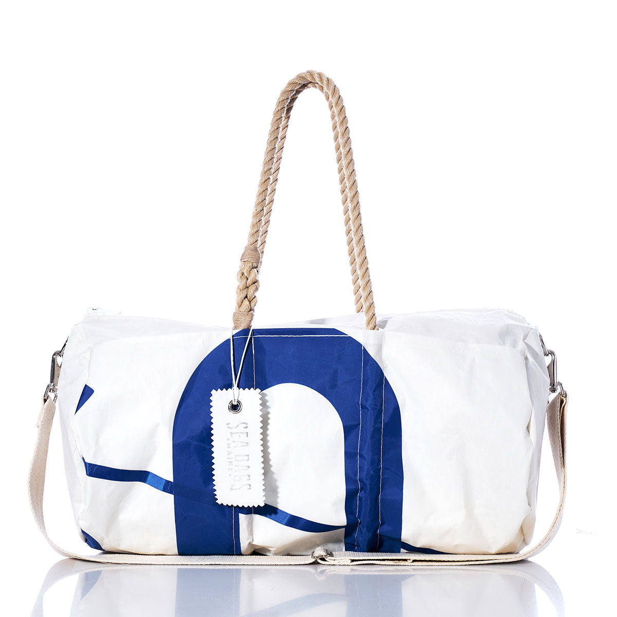The Vintage Blue U Duffel by Sea Bags is a white and blue vintage duffel bag made from recycled sail cloth, featuring durable hemp rope handles, a practical shoulder strap, and a white Sea Bags tag attached to the handle. by Sea Bags