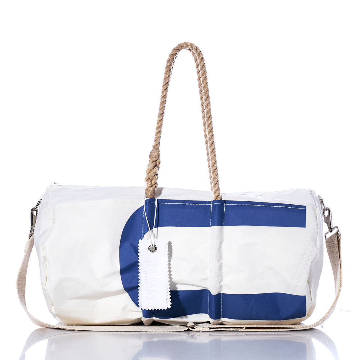 Sea Bags Vintage US Duffel, made from recycled sail cloth, features a blue geometric design, rope handles, a canvas shoulder strap, and a white tag; photographed on a white background. by Sea Bags