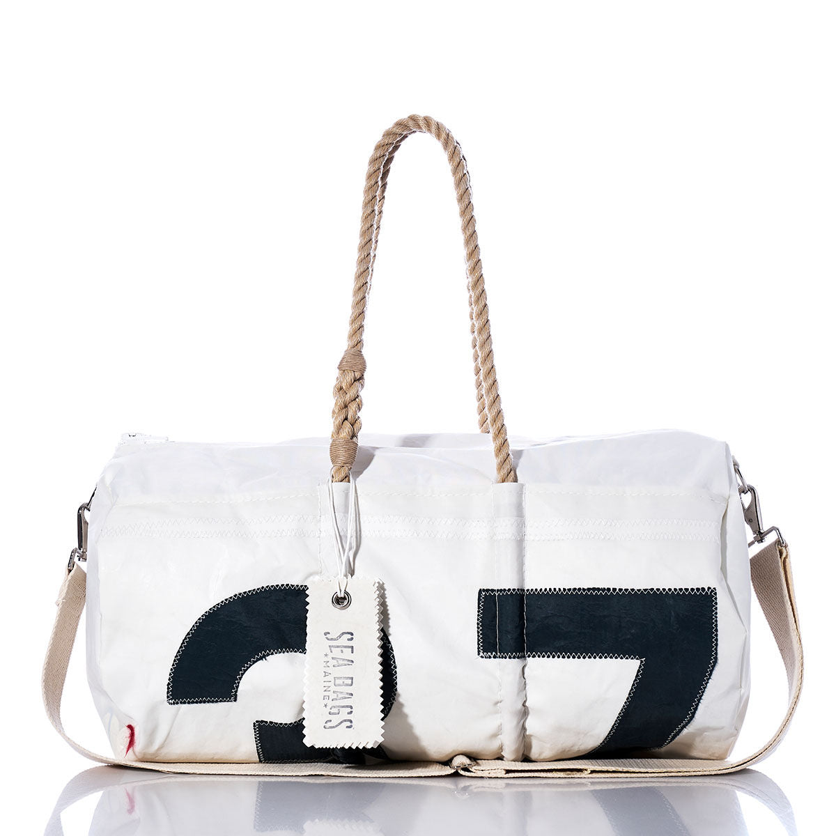 The Vintage Black 37 Duffel from Sea Bags is a white, vintage-style duffel bag crafted from recycled sail cloth. It features hemp rope handles, a beige shoulder strap, and a prominent black number 37 design. A SEA BAGS tag is attached to the handle. by Sea Bags