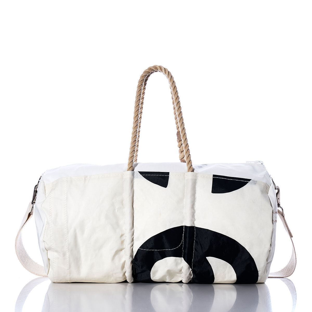 The Sea Bags Vintage 89 Duffel is a white duffel bag made from recycled sail cloth, showcasing a bold black abstract design. It features distinctive rope handles, a fabric shoulder strap, and subtle sail insignias, all presented against a white background. by Sea Bags