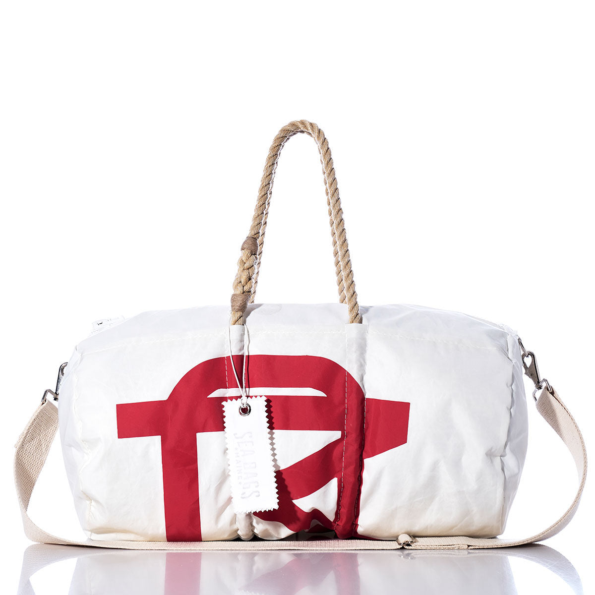 The Sea Bags Vintage Melges Duffel is a white duffel bag made from recycled sail cloth, adorned with bold red graphic accents. It features hemp rope handles, a beige shoulder strap, and a white hang tag—captured in a photograph set against a white background. by Sea Bags