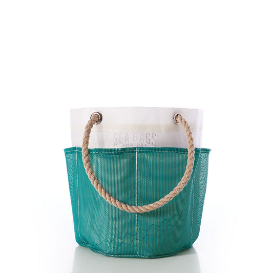 The Ocean Teal Gardeners Bucket Bag by Sea Bags features a white upper section subtly displaying the Sea Bags logo and a teal lower section. Standing upright on a white surface, this tote is designed with durable mesh for breathability and longevity. With ample space for carrying gardening essentials, it’s an ideal choice for any gardener’s bucket list. by Sea Bags