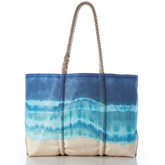 Introducing the Shoreline Tie Dye Large Tote with Clasp and Hanging Pocket from Sea Bags—a blue and beige canvas beach tote crafted from water-resistant recycled sail cloth. Featuring sturdy rope handles and a unique watercolor design inspired by ocean waves and sand, this eco-friendly bag is both stylish and practical—perfect for your seaside adventures. by Sea Bags
