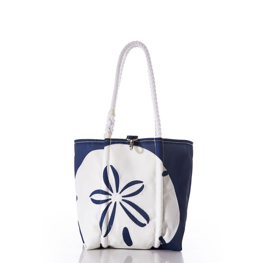The Sea Bags White on Navy Sand Dollar Handbag is an eco-friendly tote bag crafted from recycled sail cloth, featuring sturdy rope handles and a bold sand dollar design on the front in white and navy blue, photographed against a white background. by Sea Bags