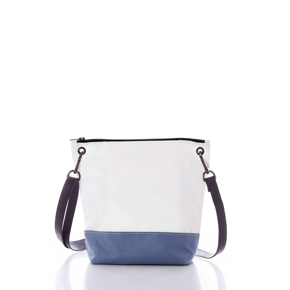 The Chambray Blue Chebeague Crossbody Bag from Sea Bags—a small bucket-style bag from the Chebeague Collection—features a white upper section with a blue bottom reminiscent of a nautical bag, accented by a black zipper and dark adjustable shoulder strap. Crafted from recycled sail cloth, it is photographed on a white background. by Sea Bags