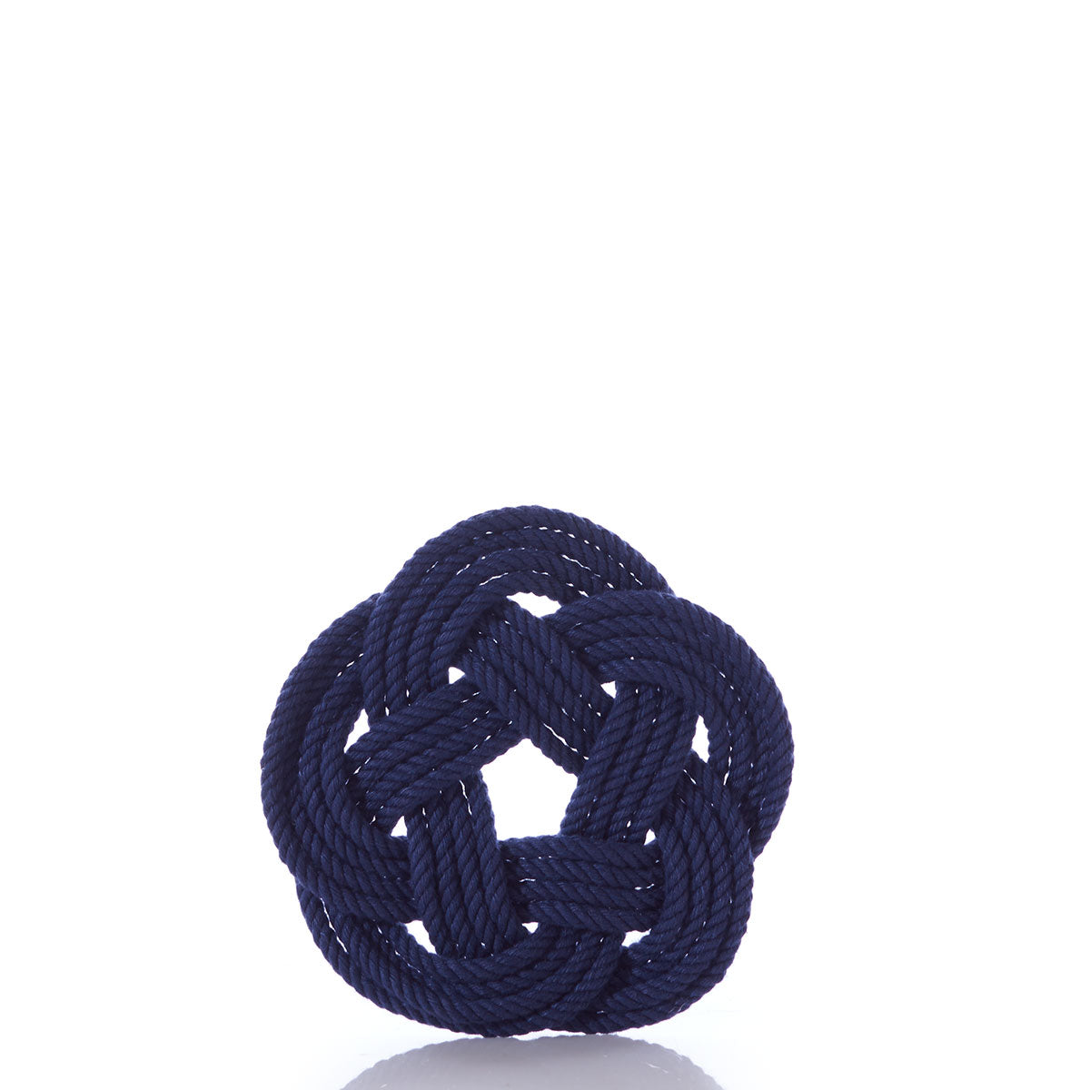 A navy blue rope, skillfully tied into a decorative Turk’s head knot, is set against a plain white background—capturing the timeless style of Nautical Sailor Knot Coasters-Navy by Mystic Knotwork.