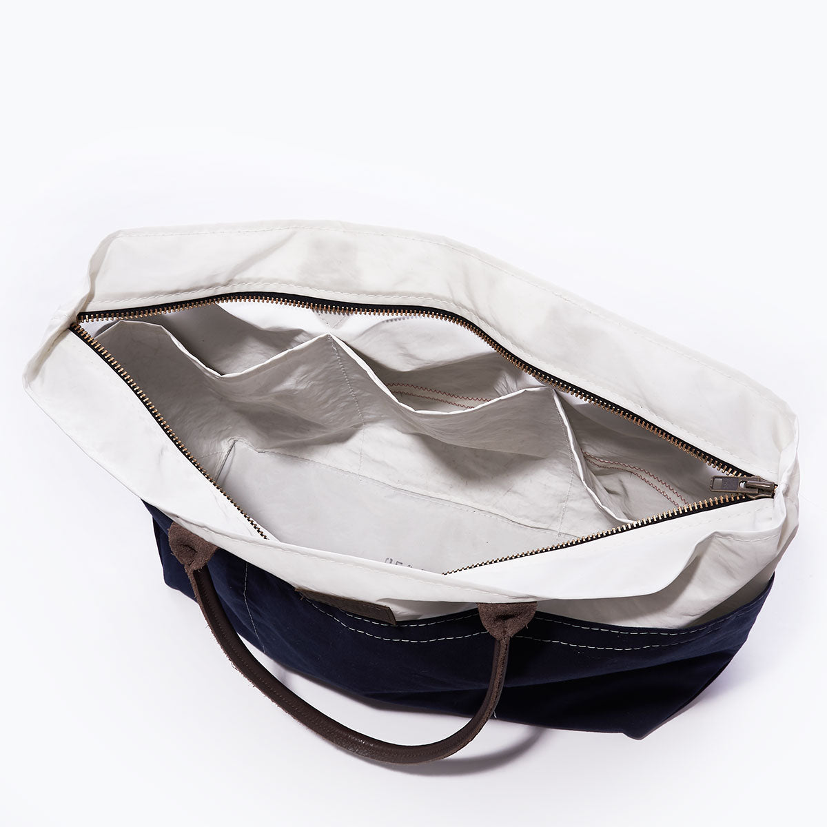 Top view of the Sea Bags Chebeague Large Travel Tote, crafted from water-resistant canvas with a white interior, dark handles, and multiple inner pockets—including a zippered compartment—making it an ideal travel carry-on. by Sea Bags