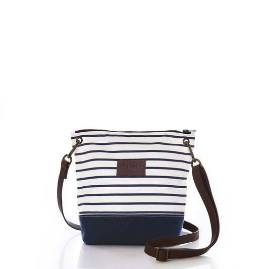 The Navy Mariner Stripe Chebeague Crossbody Bag from Sea Bags features white and navy stripes, is crafted from recycled sailcloth, and comes with a brown adjustable strap, zipper closure, and a brown patch label on the front. by Sea Bags