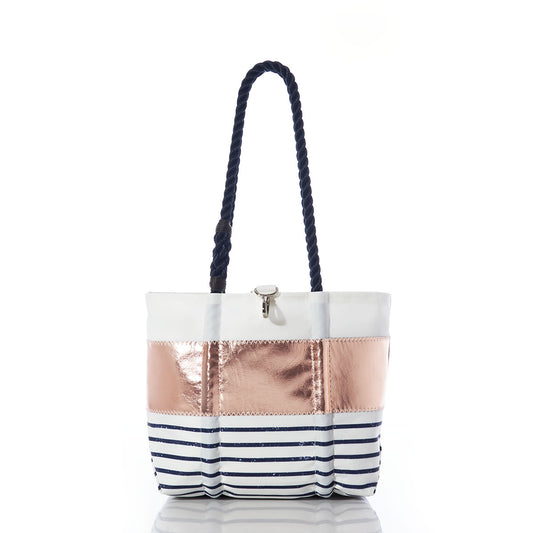 The Sea Bags Rose Gold-on-Navy Mariner Stripe Handbag features eco-friendly sail cloth, navy rope handles, a crisp white top, a striking rose gold metallic center, and a navy blue and white striped bottom. Shown on a white background, this stylish handbag is perfect for your everyday adventures while supporting sustainability. by Sea Bags