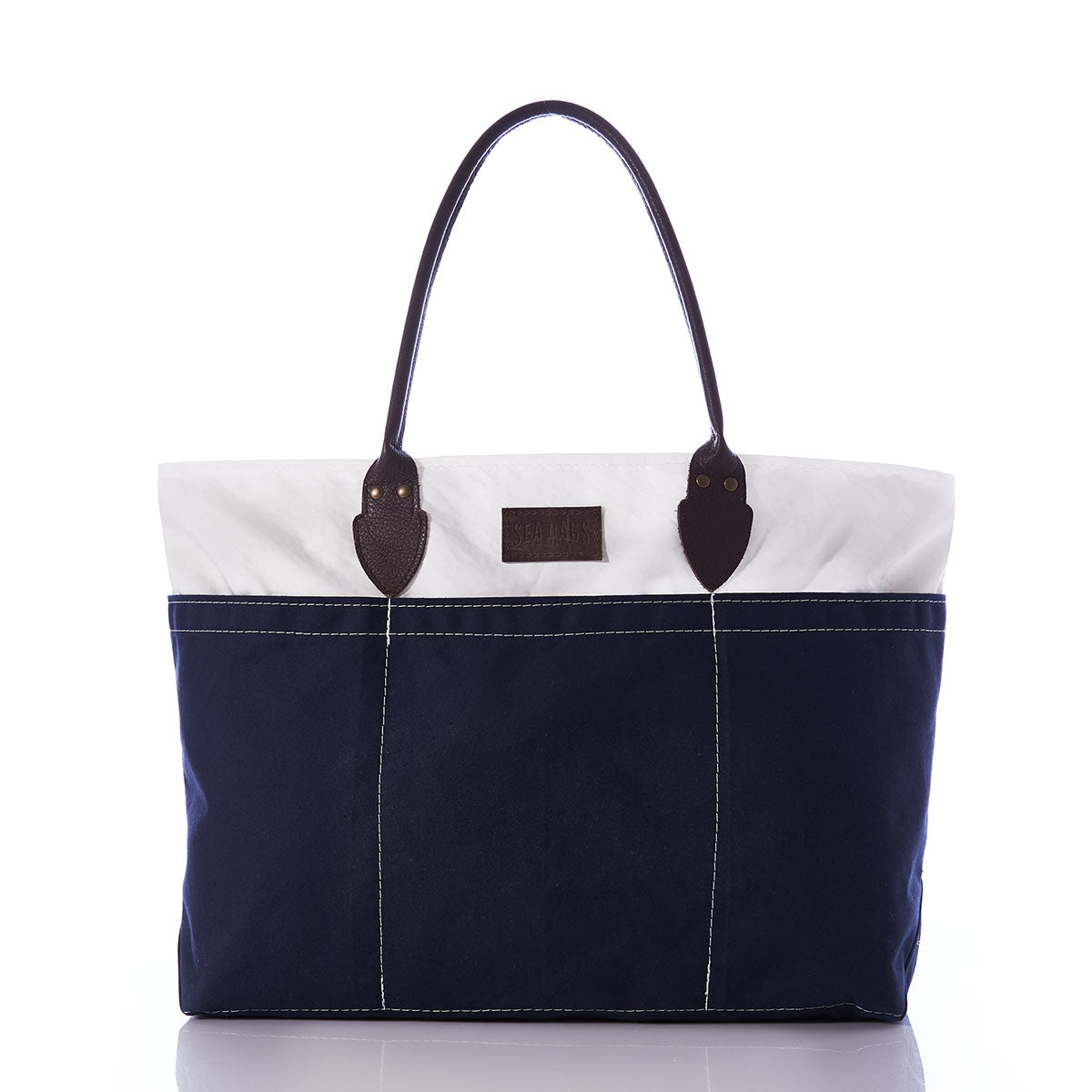 The Chebeague Large Travel Tote by Sea Bags is a spacious, water-resistant canvas bag featuring dark handles, a white upper section, and a navy blue lower section, showcased against a white background. by Sea Bags