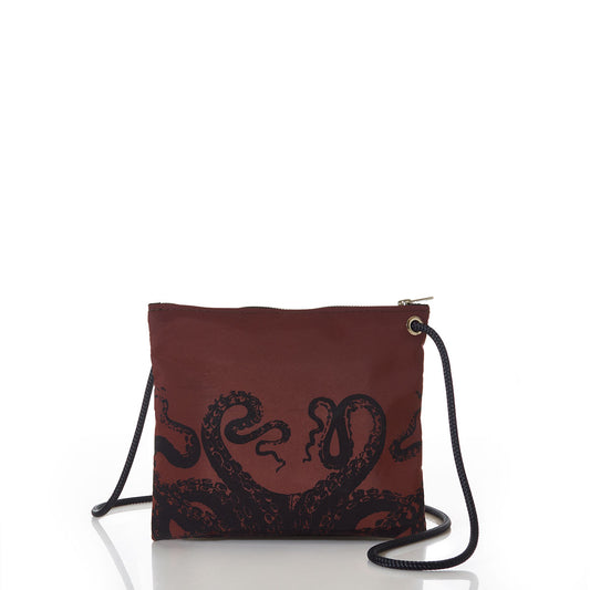 The Sea Bags Tanbark Octopus Slim Crossbody Bag features a striking black octopus tentacle design on maroon recycled sail cloth, with a zipper closure and thin black strap, offering distinctive nautical style. Photographed on a white background. by Sea Bags