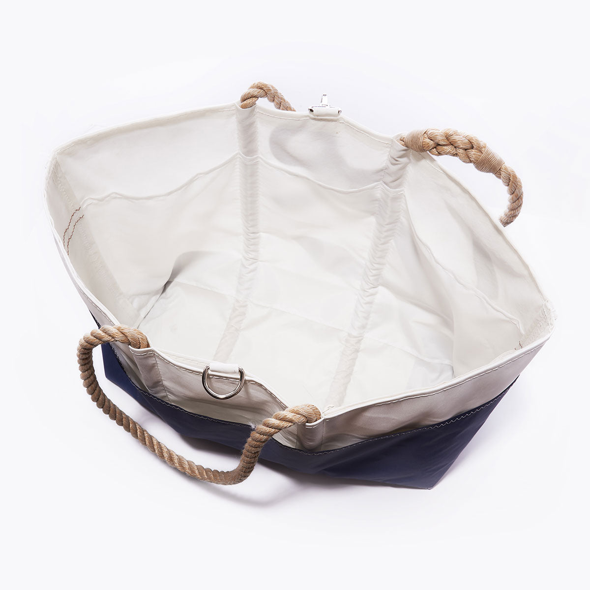 Sea Bags Navy Anchor Ogunquit Beach Tote, featuring a blue exterior base crafted from recycled sail cloth, a white interior, and tan rope handles, is displayed from a top-down perspective on a plain white background. by Sea Bags