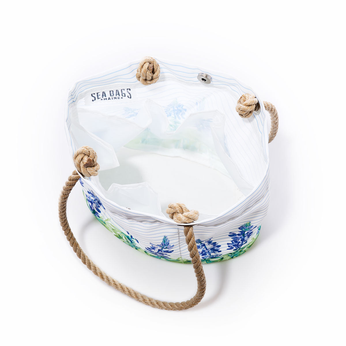 Lupine on Sailor Stripe Essential Handbag by Sea Bags—a lightweight white canvas tote crafted from recycled sail cloth, featuring rope handles, a blue and green floral pattern on sailor stripes, and signature Sea Bags branding inside; shown from above against a white background. by Sea Bags