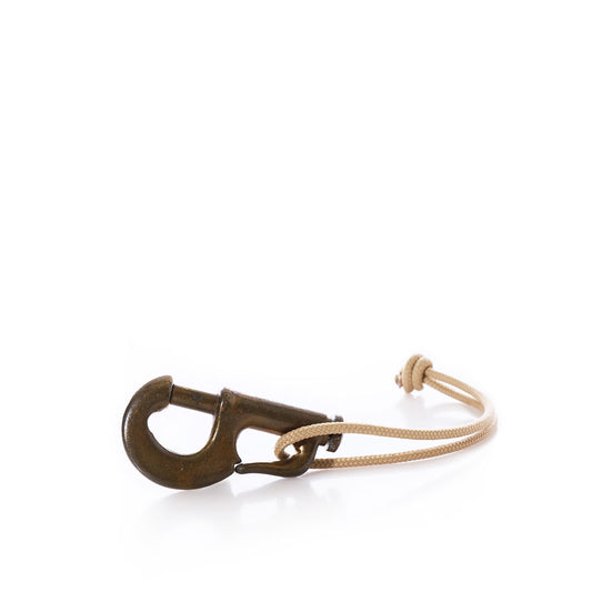 A classic piece of Vintage Sailmakers Hardware, featuring a brass jib hank snap hook paired with a beige hemp cording threaded through its eye, displayed on a white background. by Sea Bags