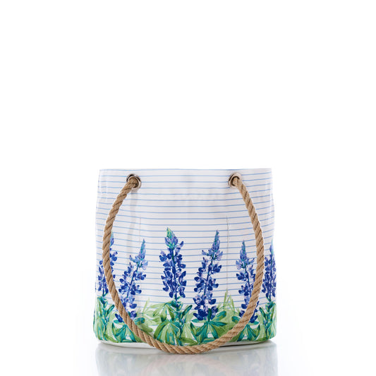Introducing the Sea Bags Lupine on Sailor Stripe Essential Handbag—a white tote featuring a captivating blue floral lupine design over classic horizontal sailor stripes. Crafted from recycled sail cloth for an eco-friendly touch, this lightweight and practical handbag boasts two sturdy rope handles. Perfect for everyday use and displayed elegantly against a white background. by Sea Bags