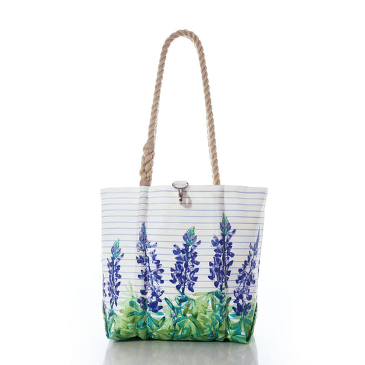 The Lupine Sailor Stripe Handbag by Sea Bags features a white recycled sail cloth design adorned with bluebonnet flower prints, green leaves, blue stripes, tan rope handles, and a silver clasp—shown here against a white background. by Sea Bags