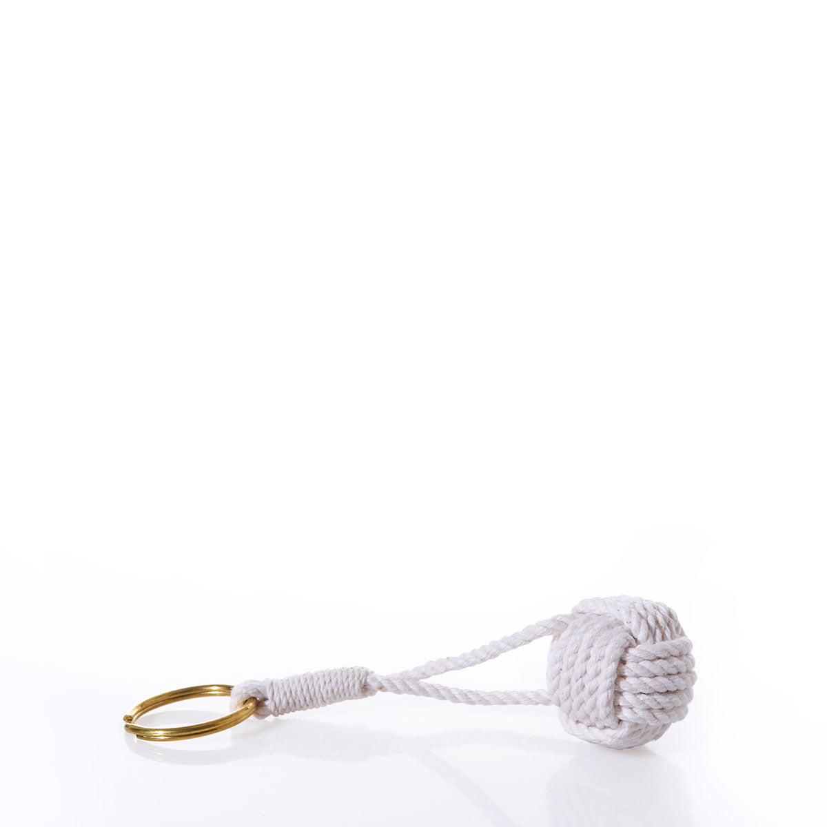 The Monkeys Fist Keychain-Natural by Mystic Knotwork features a solid brass keyring secured to a natural white cotton cord, expertly tied in the classic monkey’s fist knot. This elegant nautical keychain is photographed against a crisp white background. by Sea Bags