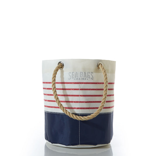 The Red Mariner Stripe Beverage Bucket Bag by Sea Bags features a white and navy canvas design with bold red horizontal stripes, sturdy rope handles, and Sea Bags printed on the upper section. Made from recycled sail cloth, this bag offers both durability and distinctive coastal charm. by Sea Bags