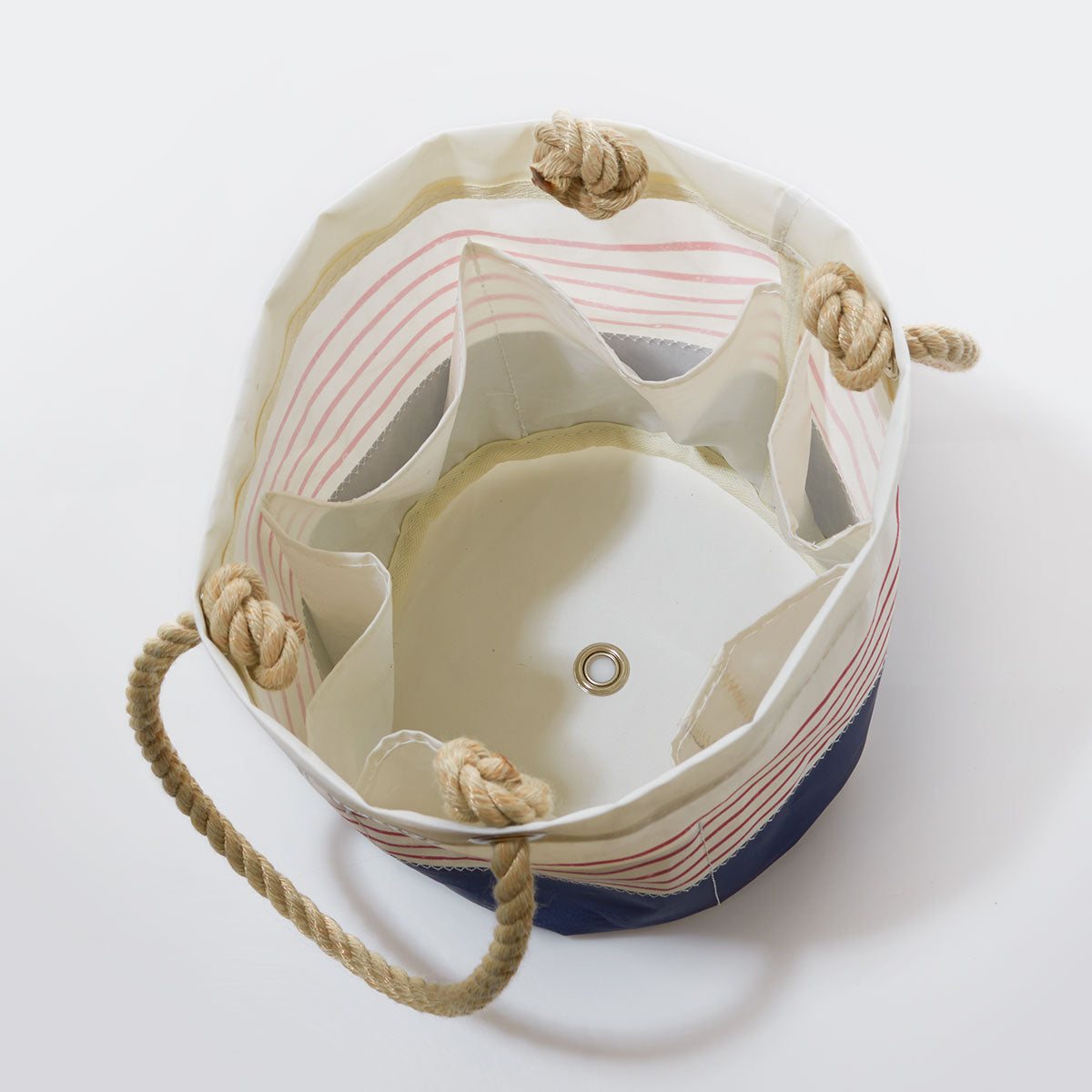 Sea Bags Red Mariner Stripe Beverage Bucket Bag is crafted from recycled sail cloth, features sturdy rope handles, interior pockets, and a metal grommet at the base—making it the perfect stylish collapsible cooler or beverage bucket when viewed from above. by Sea Bags