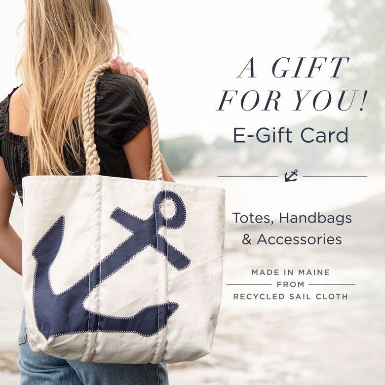 A woman holds a white tote bag adorned with a navy anchor, highlighting the perfect Maine gift: the Email a Gift Card from Sea Bags—ideal for totes, handbags, and accessories handcrafted in Maine from recycled sailcloth. by Sea Bags