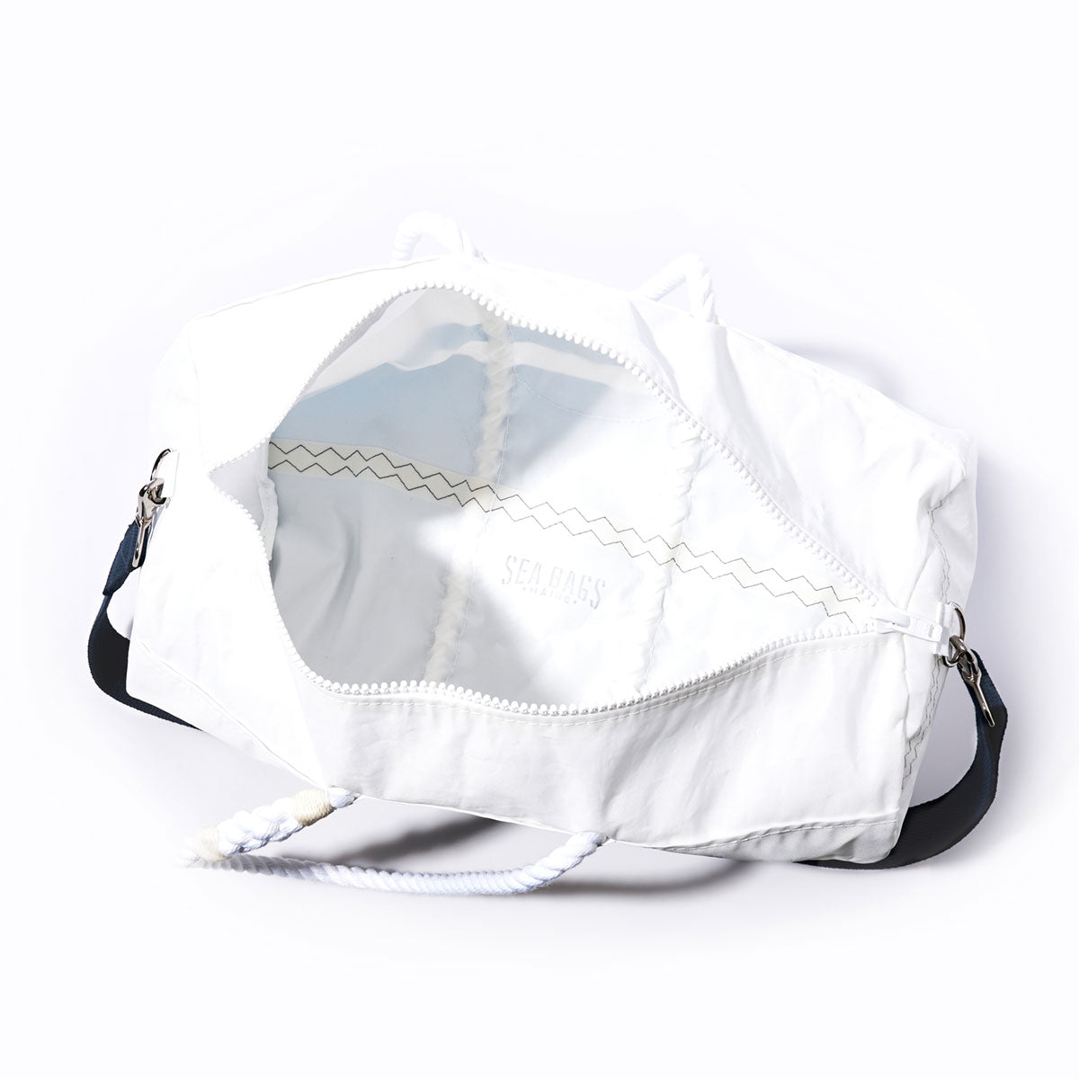 New York Giants Duffel by Sea Bags with a rope handle, unzipped to reveal its empty interior and the word SEABAGS visible inside. Crafted from recycled sail cloth, this bag features navy accents and silver hardware. by Sea Bags