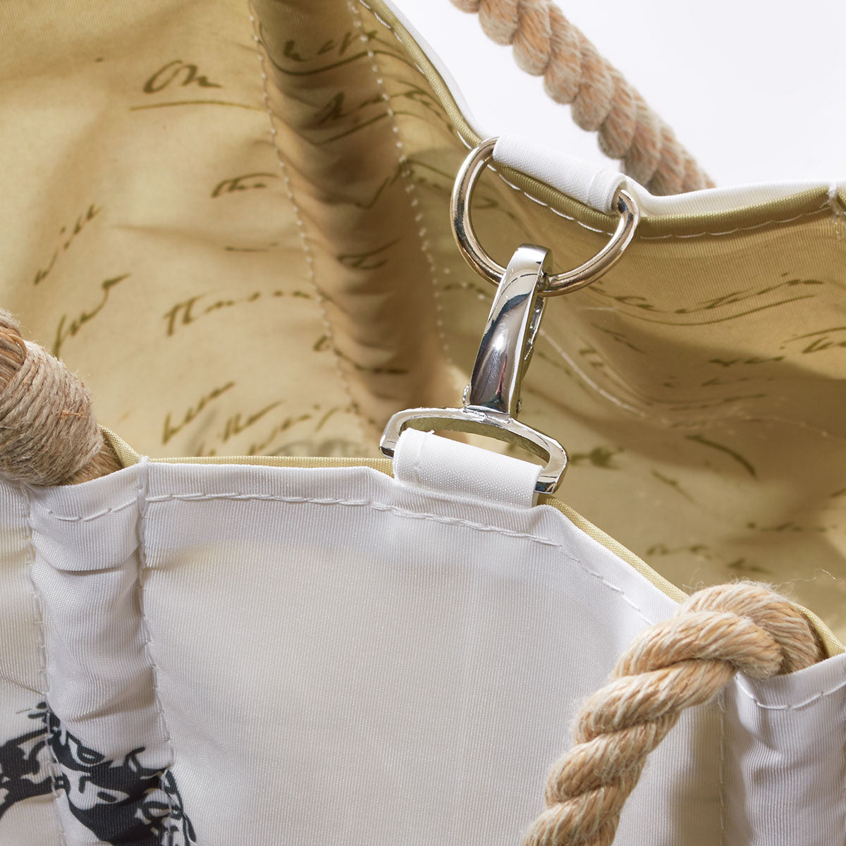 Close-up of the interior of a Sea Bags Octopus Handbag, crafted from recycled sail cloth and featuring rope handles. The photo highlights a metal clasp attached to a fabric loop and showcases a printed lining with script inspired by Charles Darwin’s handwritten notes. by Sea Bags