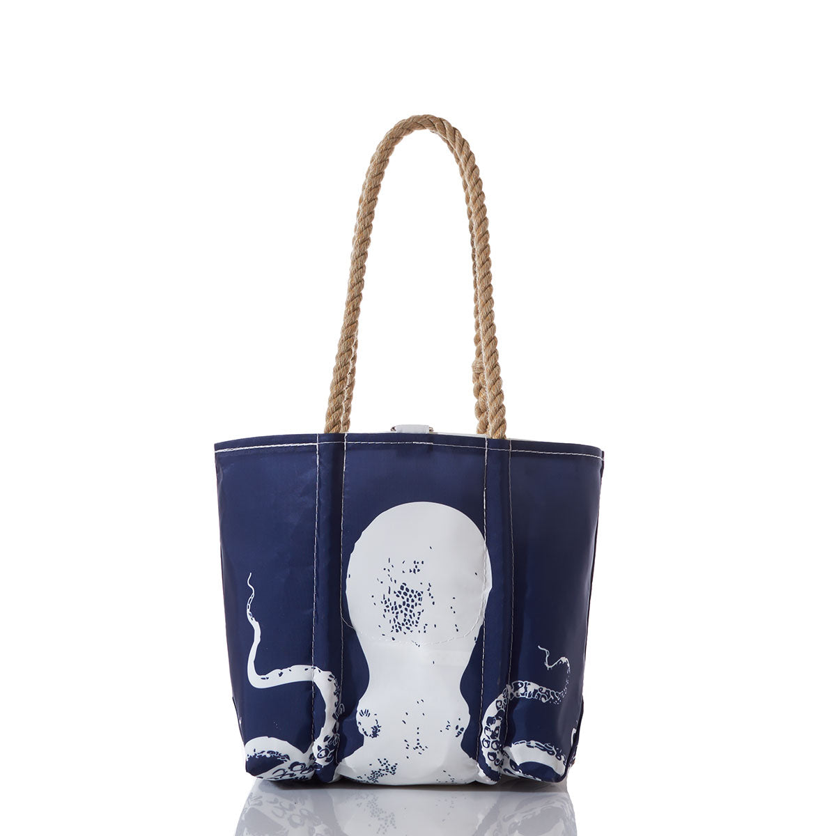 Sea Bags White on Navy Octopus Handbag features a white octopus graphic on a navy blue background, complemented by sturdy rope handles. Displayed on a white background with a subtle reflection beneath, this elegant handbag captures the spirit of oceanography and maritime adventures. by Sea Bags