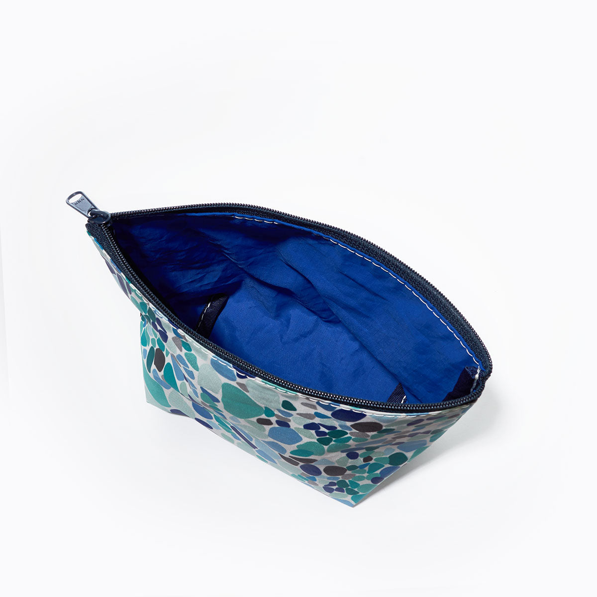 The Sea Glass Print Cosmetic Bag by Sea Bags features a zippered design with a blue and green abstract pattern inspired by sea glass, and is shown open to reveal its rare blue interior lining. by Sea Bags