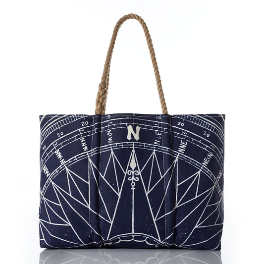 Introducing the Navy True North Large Tote by Sea Bags—a spacious navy blue tote crafted from recycled sailcloth, featuring a striking white nautical compass rose design and brown braided handles. Displayed against a white background, its the perfect nautical gift. by Sea Bags