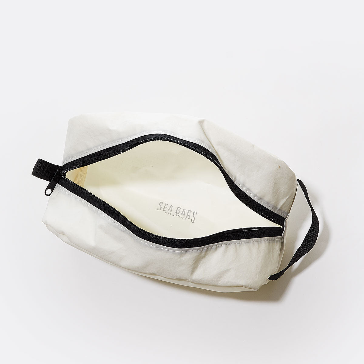 White zippered Paw Print Toiletry Bag by Sea Bags with a black handle, shown open and empty on a plain white background. Made from recycled sail cloth, this travel kit is ideal for dog lovers and features the Sea Bags logo inside. by Sea Bags