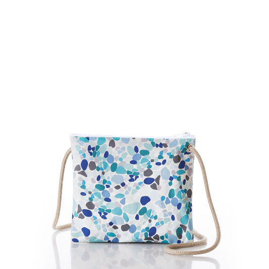 The Sea Glass Print Slim Crossbody by Sea Bags is a small crossbody bag made from recycled sail cloth, showcasing a blue and teal abstract pebble pattern inspired by sea glass hues. It features a rope strap and white zipper, and is one of our beautiful accessories displayed against a plain white background. by Sea Bags