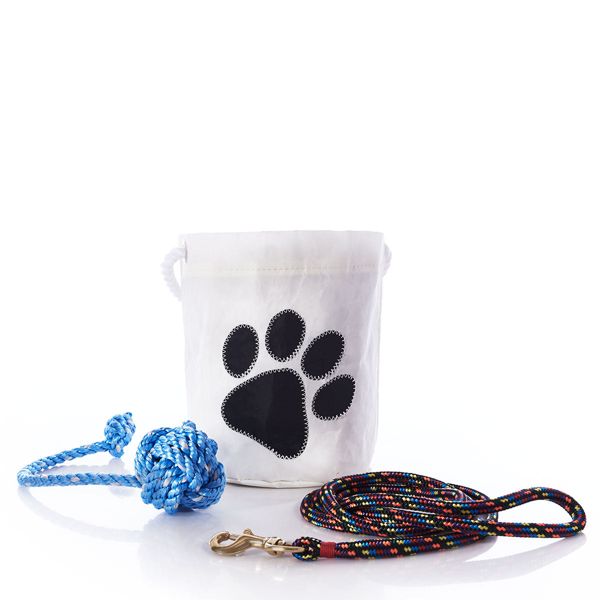 A white bag featuring a black paw print, a Fetch ME Floating Rope Dog Toy in yellow handmade in Maine, and a multicolored dog leash with a metal clasp, all arranged on a white surface. by Sea Bags