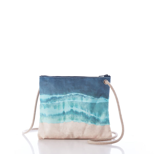 The Shoreline Tie Dye Slim Crossbody Bag by Sea Bags is crafted from recycled sail cloth and features a blue and turquoise watercolor pattern, a beige bottom, zipper closure, and a beige rope strap for stylish hands-free carrying, shown on a white background. by Sea Bags
