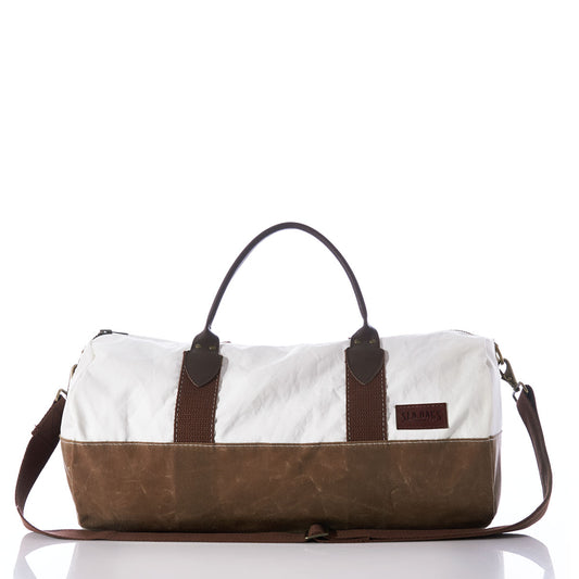 The Sea Bags Tan Chebeague Duffel, shown on a white background, is a maritime travel bag with a white canvas top, brown leather bottom, brown handles, and a detachable shoulder strap. by Sea Bags