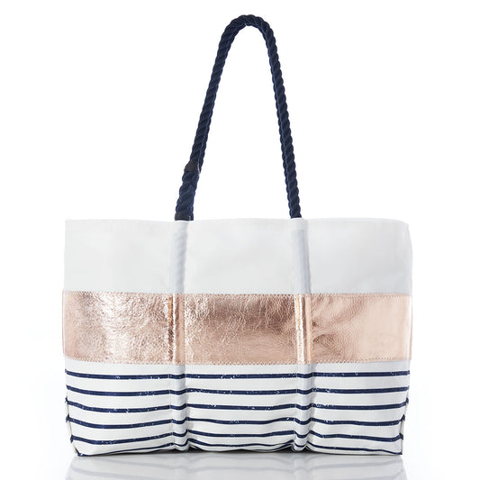 Sea Bags Rose Gold-on-Navy Mariner Stripe Large Tote, featuring navy rope handles, a metallic rose gold band, and bold navy horizontal stripes at the base, is displayed on a white background. This oversized tote combines chic style with everyday functionality for a standout look. by Sea Bags