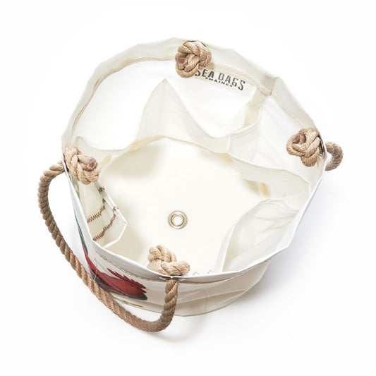 Key West Rooster Beverage Bucket by Sea Bags. Crafted from recycled sail cloth, this white bucket bag features rope handles, a metal grommet on the bottom, and SEA BAGS branding on the interior. The top edge is finished with rope loops, and the interior is open for convenient use. by Sea Bags